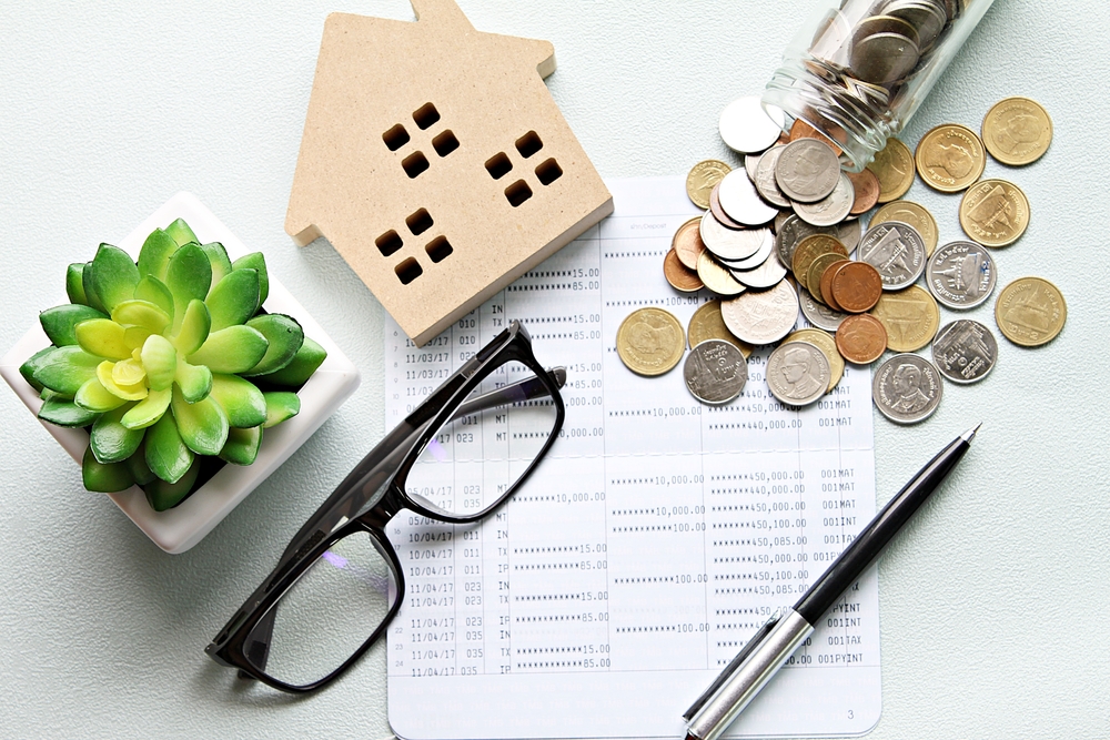 Business, finance, saving money, property ladder or mortgage loan concept : Wood house model, coins and financial statement or saving account book on desk table, cap rate