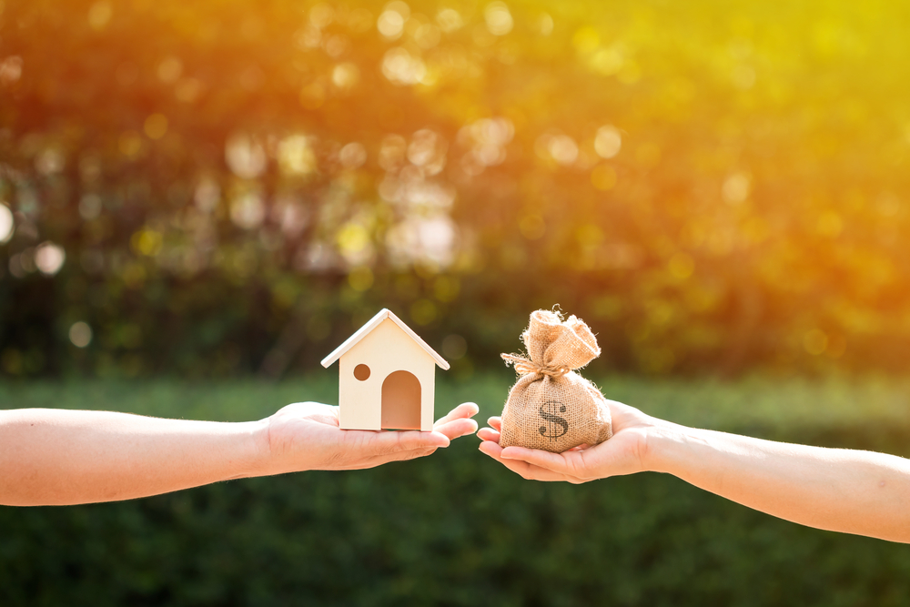 Loans for real estate concept, a man and a women hand holding a money bag and  a model home put together in the public park., Investment Lending, Real Estate Investment